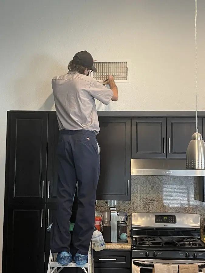 Technician inspecting an air vent during HVAC service in Dickson